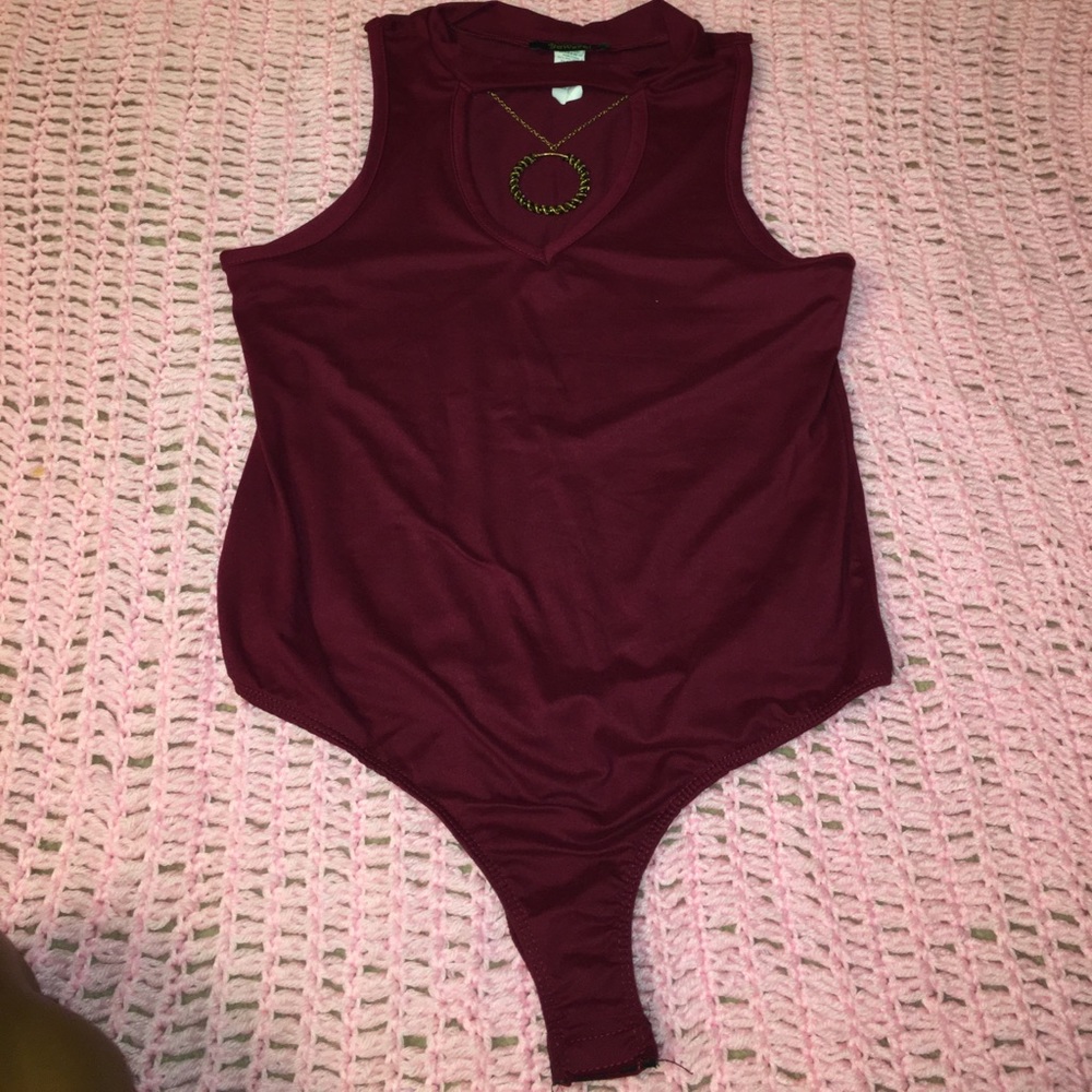 Maroon body suit with a gold/black necklace